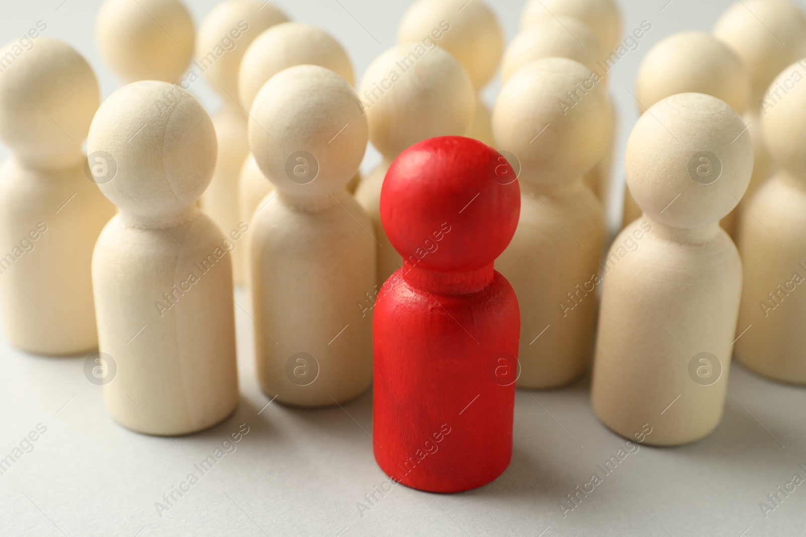 Unemployment. One red figure among wooden on light background, closeup Photo of Unemployment. One red figure among wooden on light background, closeup