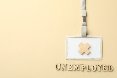 Photo of Word Unemployed, badge and cross on beige background, flat lay. Space for text