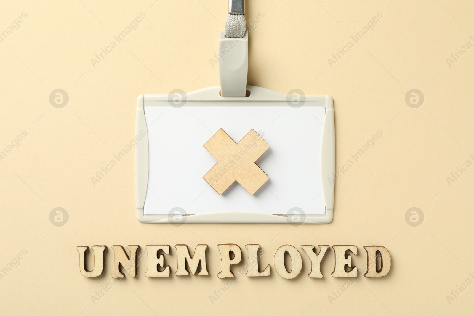 Word Unemployed, badge and cross on beige background, flat lay Photo of Word Unemployed, badge and cross on beige background, flat lay