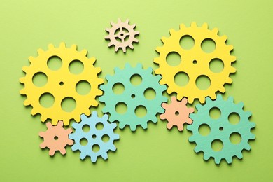 Photo of Unemployment. Gearwheels on green background, flat lay