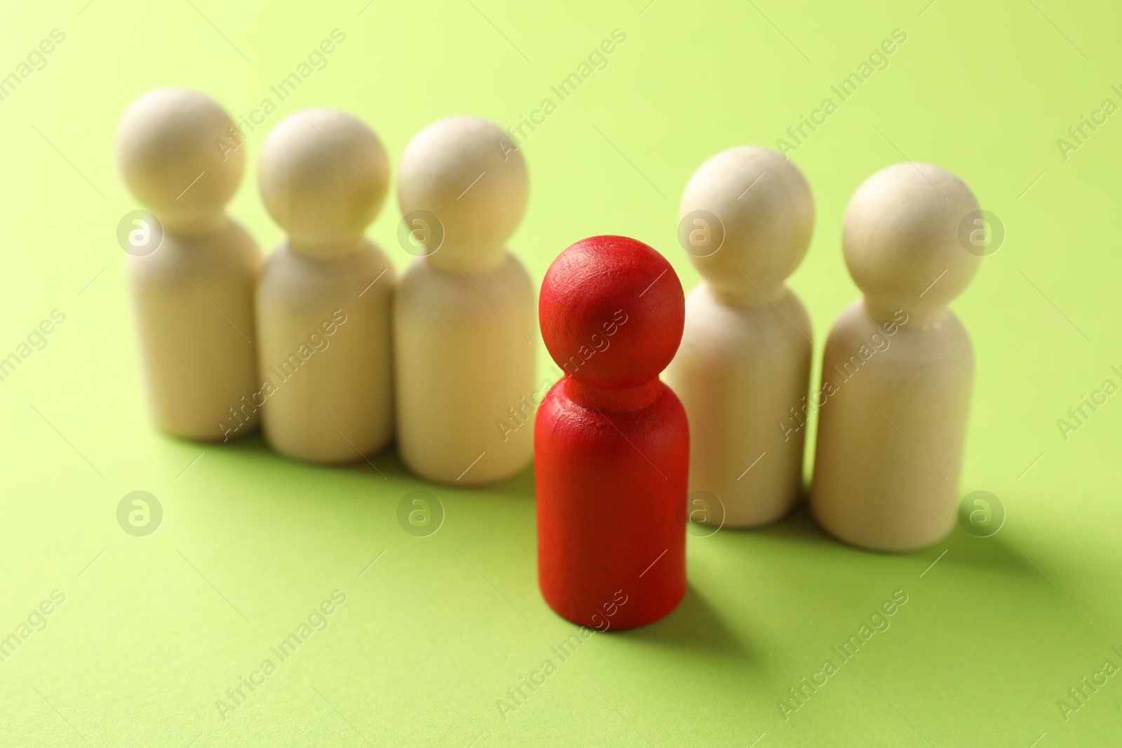 Photo of Unemployment. One red figure among wooden on green background, closeup