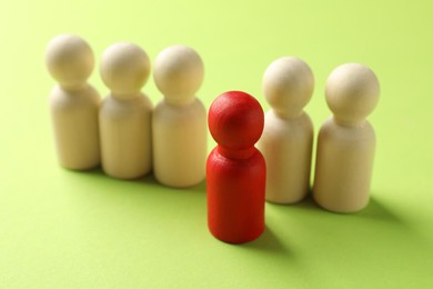 Photo of Unemployment. One red figure among wooden on green background, closeup