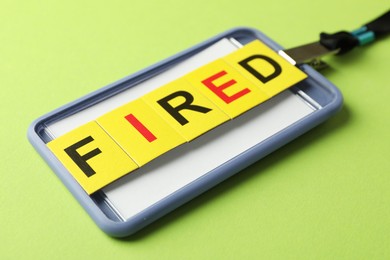 Photo of Dismissal. Word fired and badge on green background, closeup