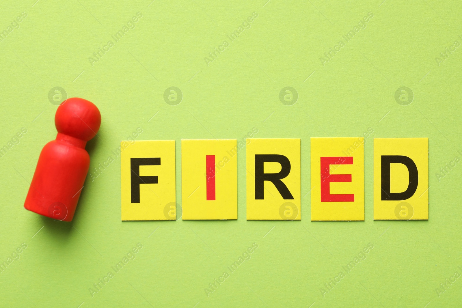 Dismissal. Word fired and human figure on green background, top view Photo of Dismissal. Word fired and human figure on green background, top view