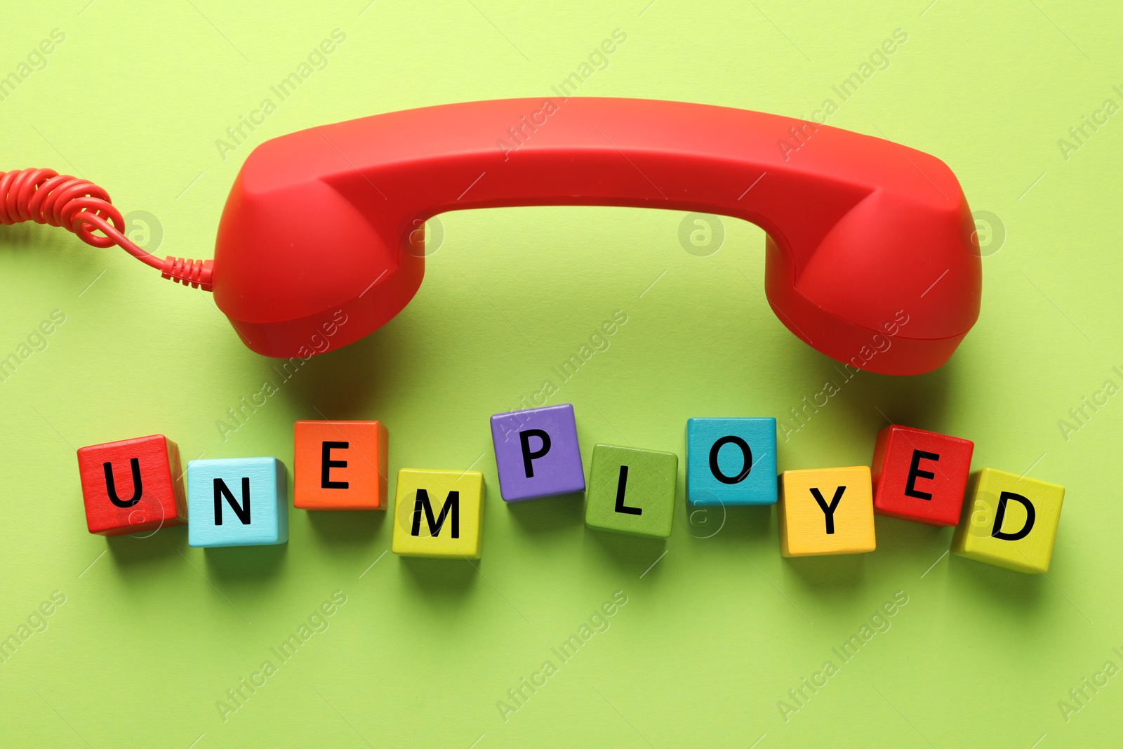 Word Unemployed and telephone handle on green background, flat lay Photo of Word Unemployed and telephone handle on green background, flat lay