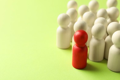 Photo of Unemployment. One red figure among wooden on green background, closeup. Space for text
