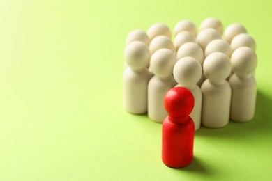 Photo of Unemployment. One red figure among wooden on green background, closeup. Space for text