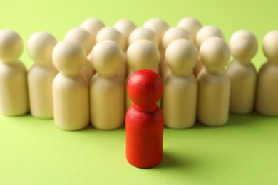 Photo of Unemployment. One red figure among wooden on green background, closeup