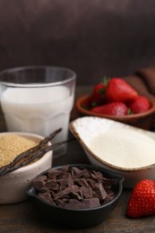 Photo of Different ingredients for panna cotta. Milk, sugar, vanilla, chocolate and strawberries on wooden table, closeup