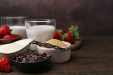 Photo of Different ingredients for panna cotta. Milk, sugar, vanilla, chocolate and strawberries on wooden table, closeup. Space for text