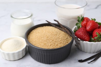 Photo of Different ingredients for panna cotta. Milk, sugar, vanilla and strawberries on white marble table, closeup
