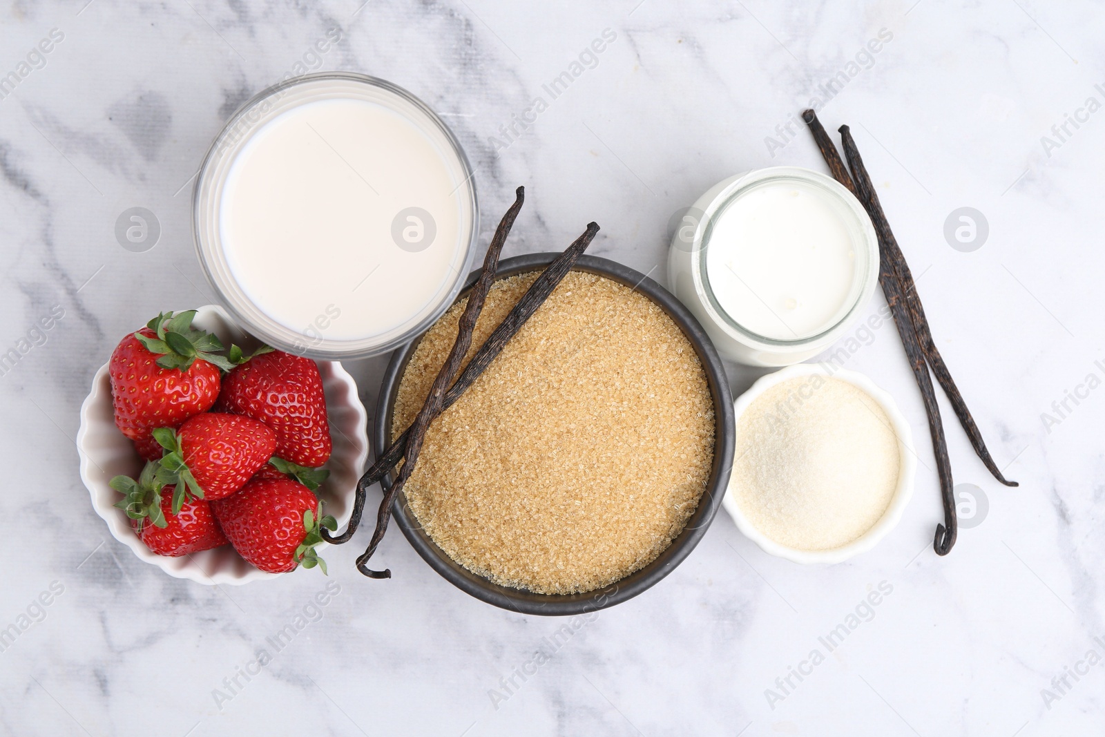 Photo of Different ingredients for panna cotta. Milk, sugar, vanilla and strawberries on white marble table, flat lay
