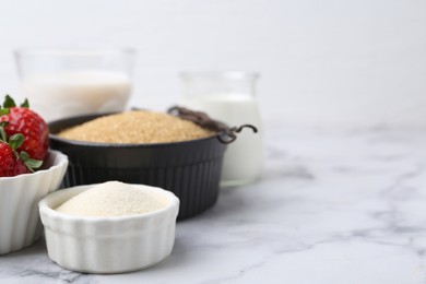 Photo of Different ingredients for panna cotta. Milk, sugar, vanilla and strawberries on white marble table, closeup. Space for text