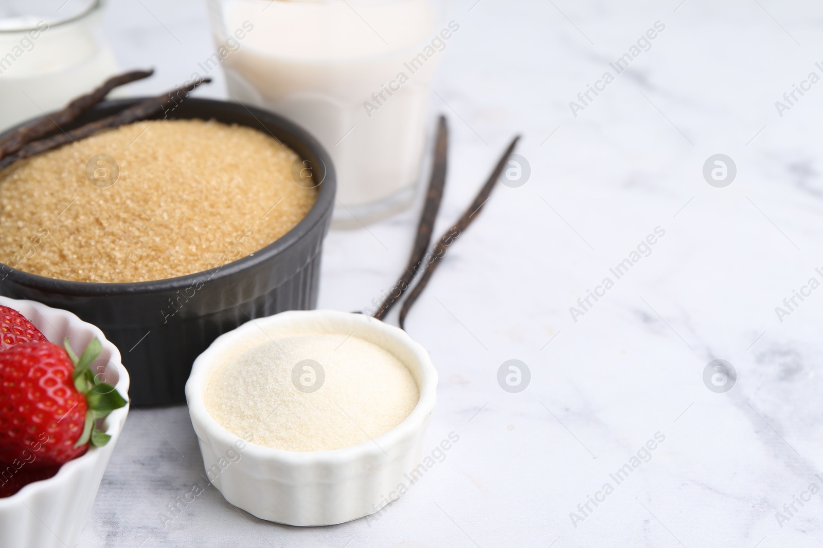 Different ingredients for panna cotta. Milk, sugar, vanilla and strawberries on white marble table, closeup. Space for text Photo of Different ingredients for panna cotta. Milk, sugar, vanilla and strawberries on white marble table, closeup. Space for text