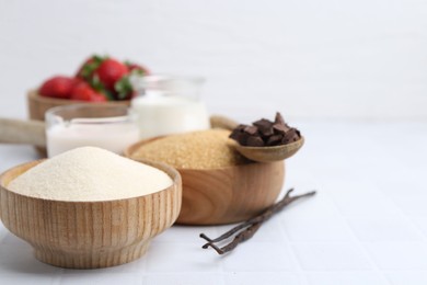 Photo of Different ingredients for panna cotta. Milk, sugar, vanilla, chocolate and strawberries on white tiled table, closeup. Space for text