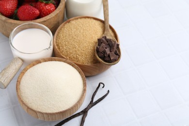 Photo of Different ingredients for panna cotta. Milk, sugar, vanilla, chocolate and strawberries on white tiled table, closeup. Space for text