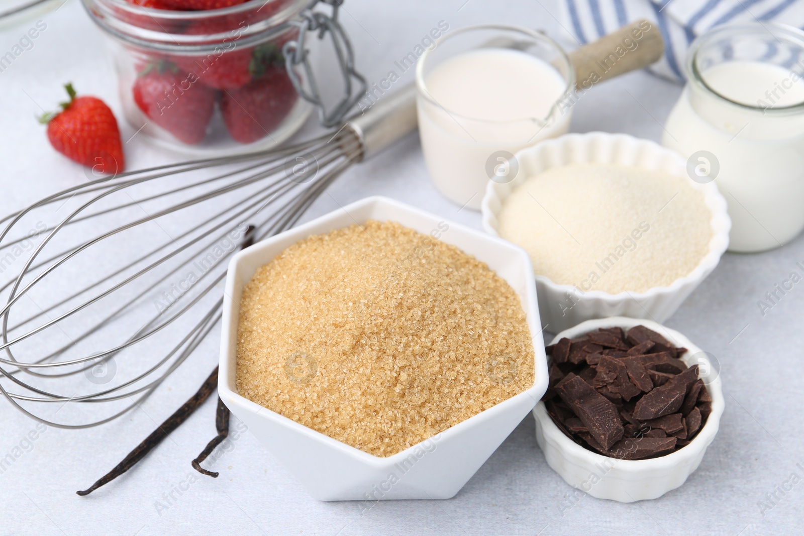 Different ingredients for panna cotta. Milk, sugar, vanilla, chocolate and strawberries on white table, closeup Photo of Different ingredients for panna cotta. Milk, sugar, vanilla, chocolate and strawberries on white table, closeup