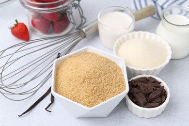 Photo of Different ingredients for panna cotta. Milk, sugar, vanilla, chocolate and strawberries on white table, closeup
