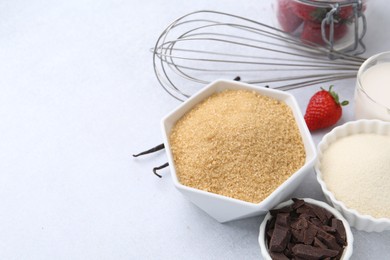 Photo of Different ingredients for panna cotta. Milk, sugar, vanilla, chocolate and strawberries on white table, closeup. Space for text