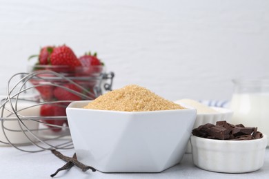 Photo of Different ingredients for panna cotta. Milk, sugar, vanilla, chocolate and strawberries on white table, closeup