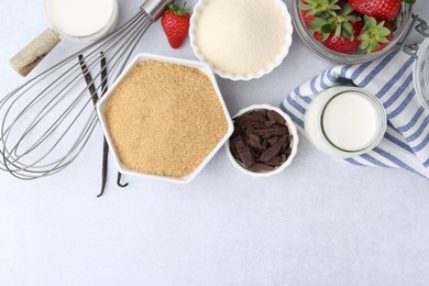 Photo of Different ingredients for panna cotta. Milk, sugar, vanilla, chocolate and strawberries on white table, flat lay. Space for text