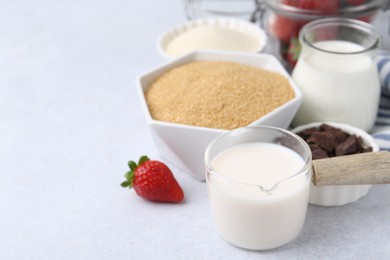 Photo of Different ingredients for panna cotta. Milk, sugar, vanilla, chocolate and strawberries on white table, closeup. Space for text