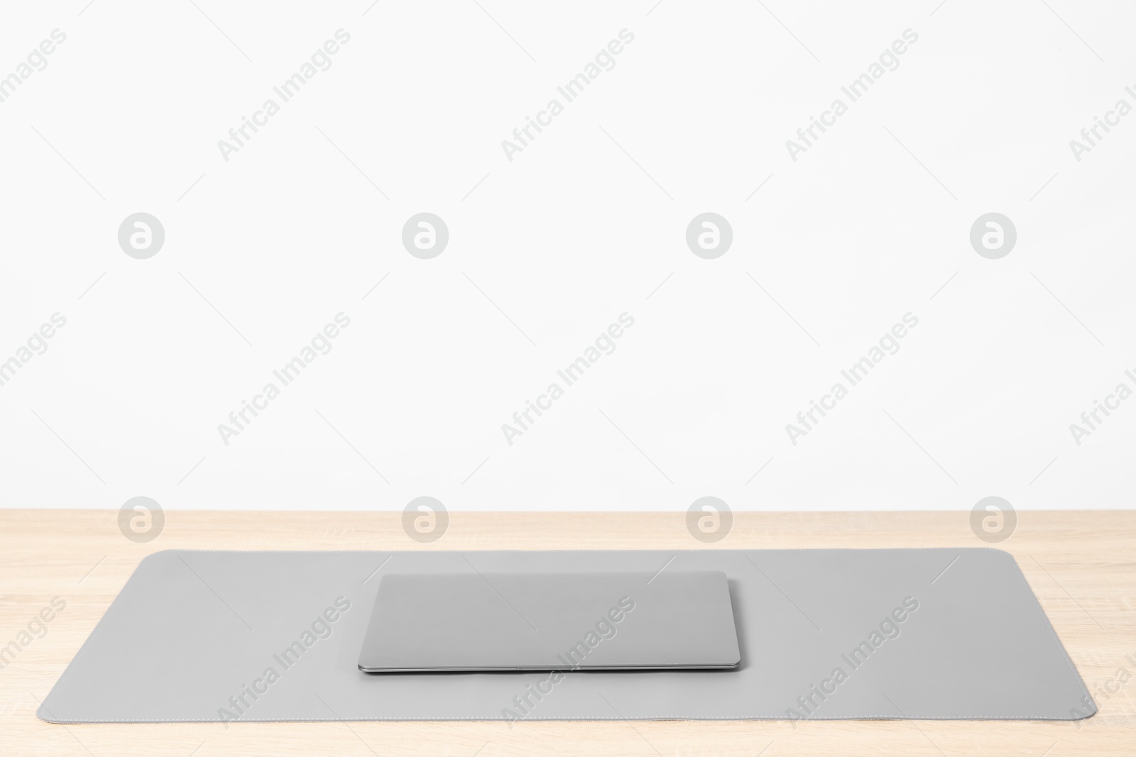 Photo of Stylish workplace with laptop and grey mousepad on wooden table indoors. Space for text