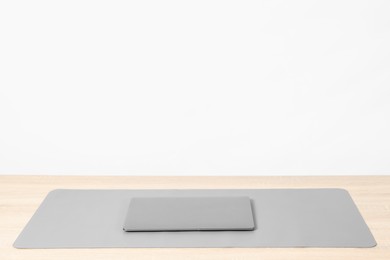 Photo of Stylish workplace with laptop and grey mousepad on wooden table indoors. Space for text