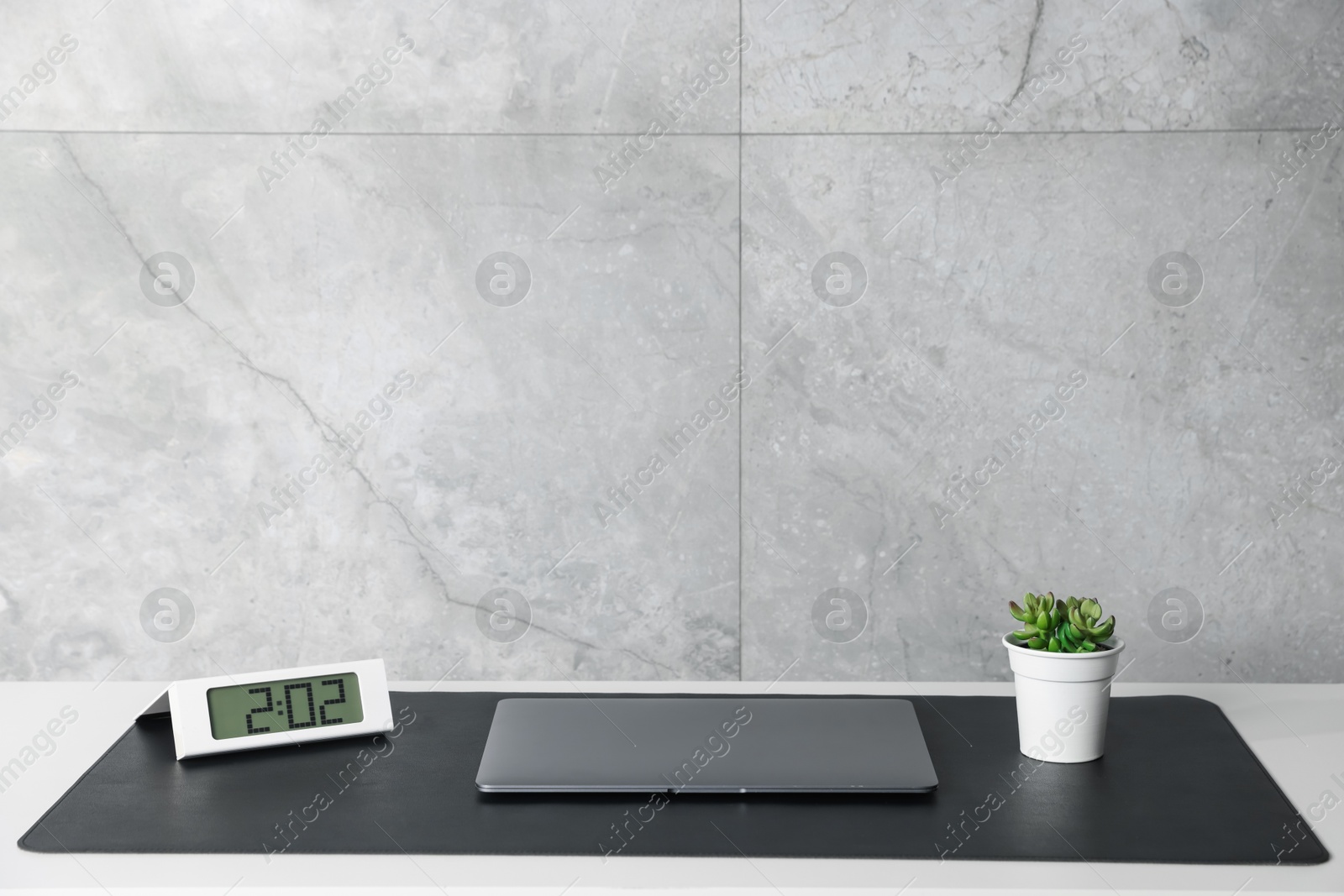 Photo of Stylish workplace with laptop and black mousepad on white table indoors. Space for text
