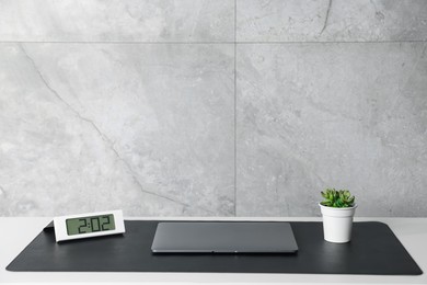 Photo of Stylish workplace with laptop and black mousepad on white table indoors. Space for text