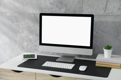 Photo of Stylish workplace with computer and black mousepad on white table indoors. Space for text