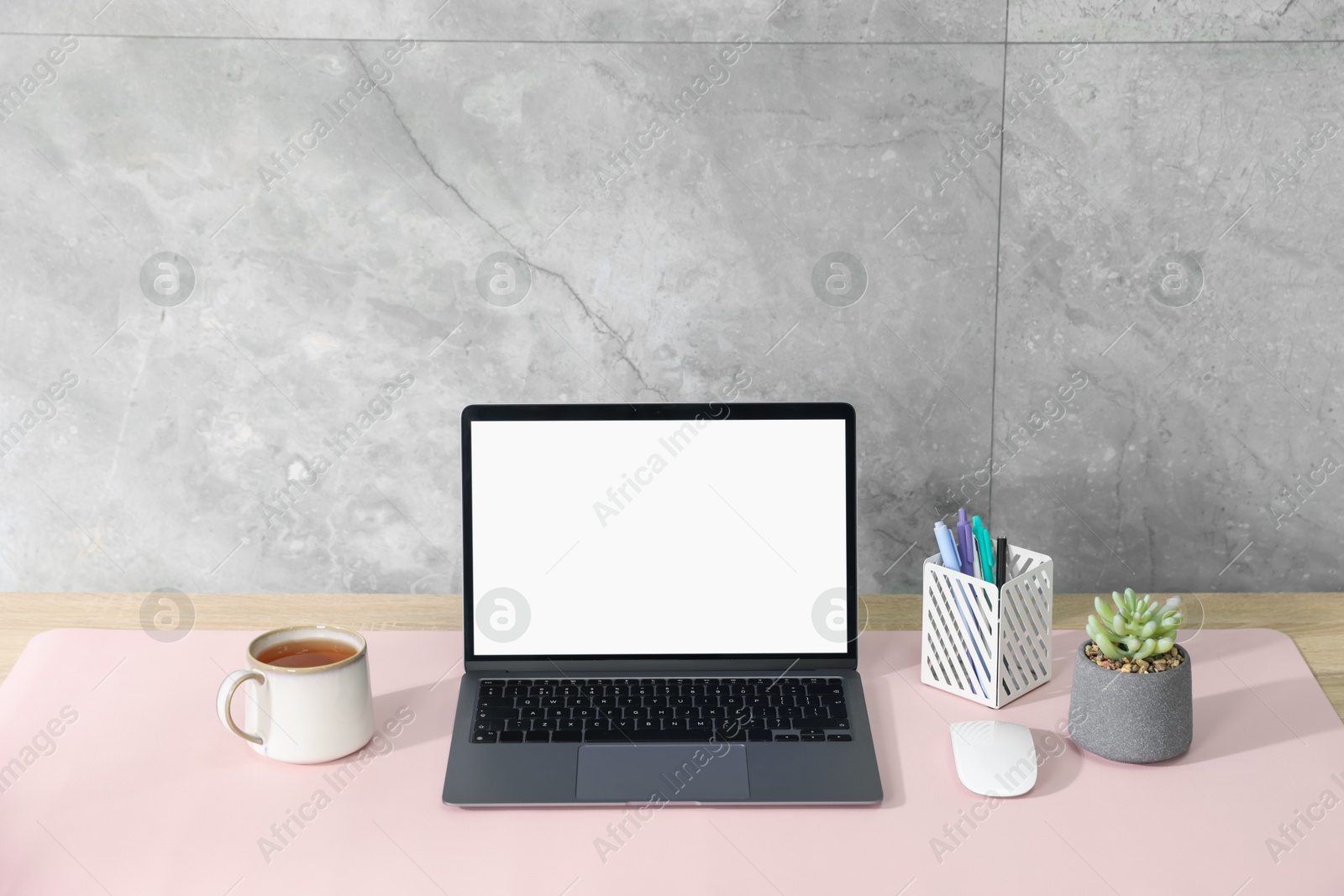 Photo of Stylish workplace with laptop and pink mousepad on white table indoors. Space for text