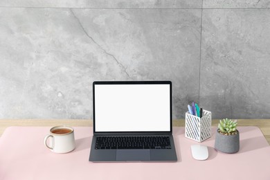 Photo of Stylish workplace with laptop and pink mousepad on white table indoors. Space for text