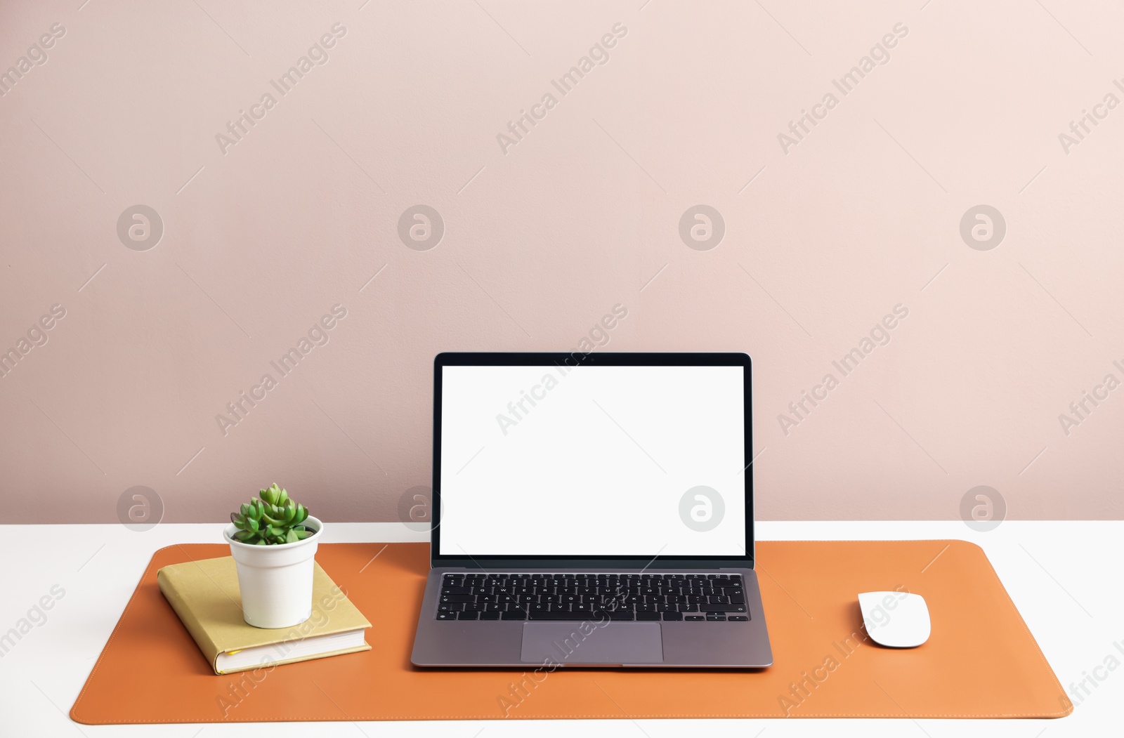 Photo of Stylish workplace with laptop and orange mousepad on white table indoors. Space for text
