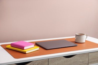 Photo of Stylish workplace with laptop and orange mousepad on white table indoors. Space for text