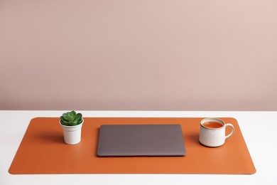 Photo of Stylish workplace with laptop and orange mousepad on white table indoors. Space for text