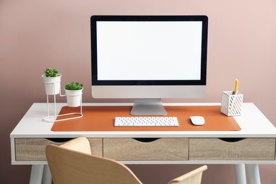 Photo of Stylish workplace with computer and orange mousepad on white table indoors. Space for text