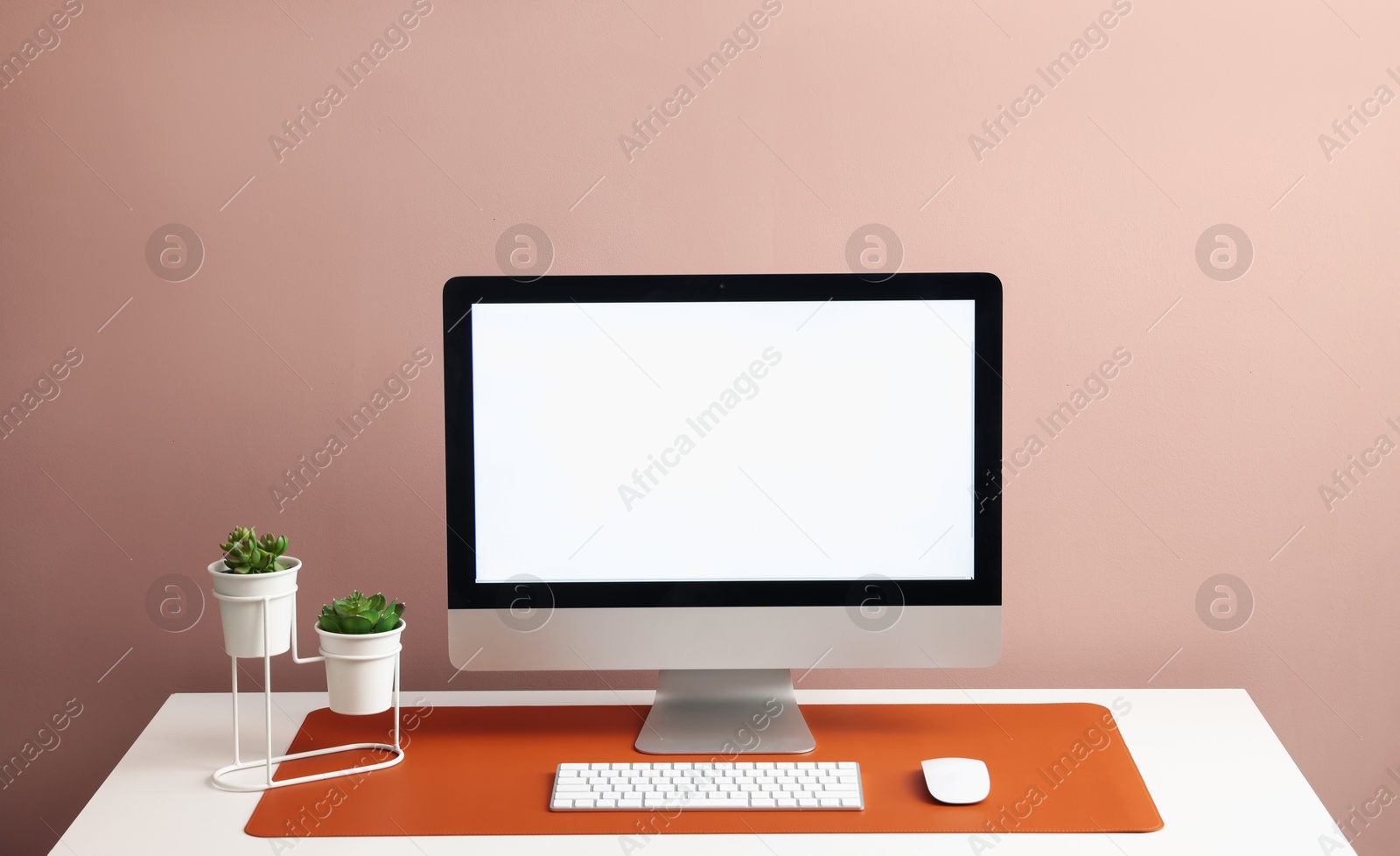 Photo of Stylish workplace with computer and orange mousepad on white table indoors. Space for text