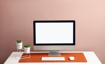 Photo of Stylish workplace with computer and orange mousepad on white table indoors. Space for text