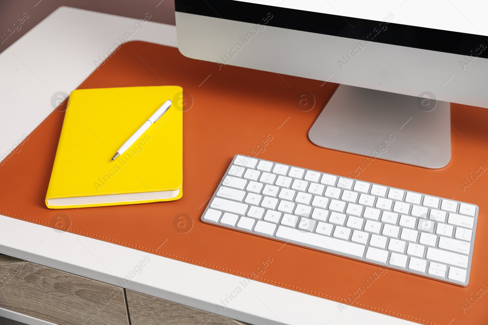 Stylish workplace with computer and orange mousepad on white table indoors, closeup Photo of Stylish workplace with computer and orange mousepad on white table indoors, closeup