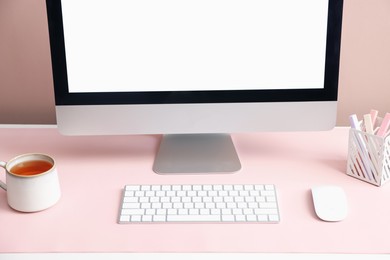 Photo of Stylish workplace with computer and pink mousepad on white table indoors, closeup. Space for text