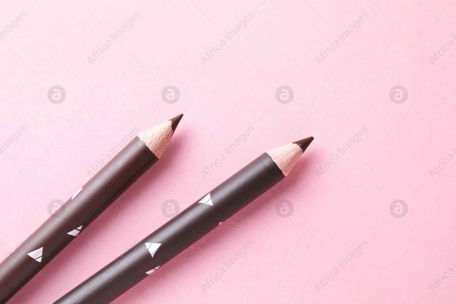 Eyebrow pencils on pink background, above view. Space for text Photo of Eyebrow pencils on pink background, above view. Space for text