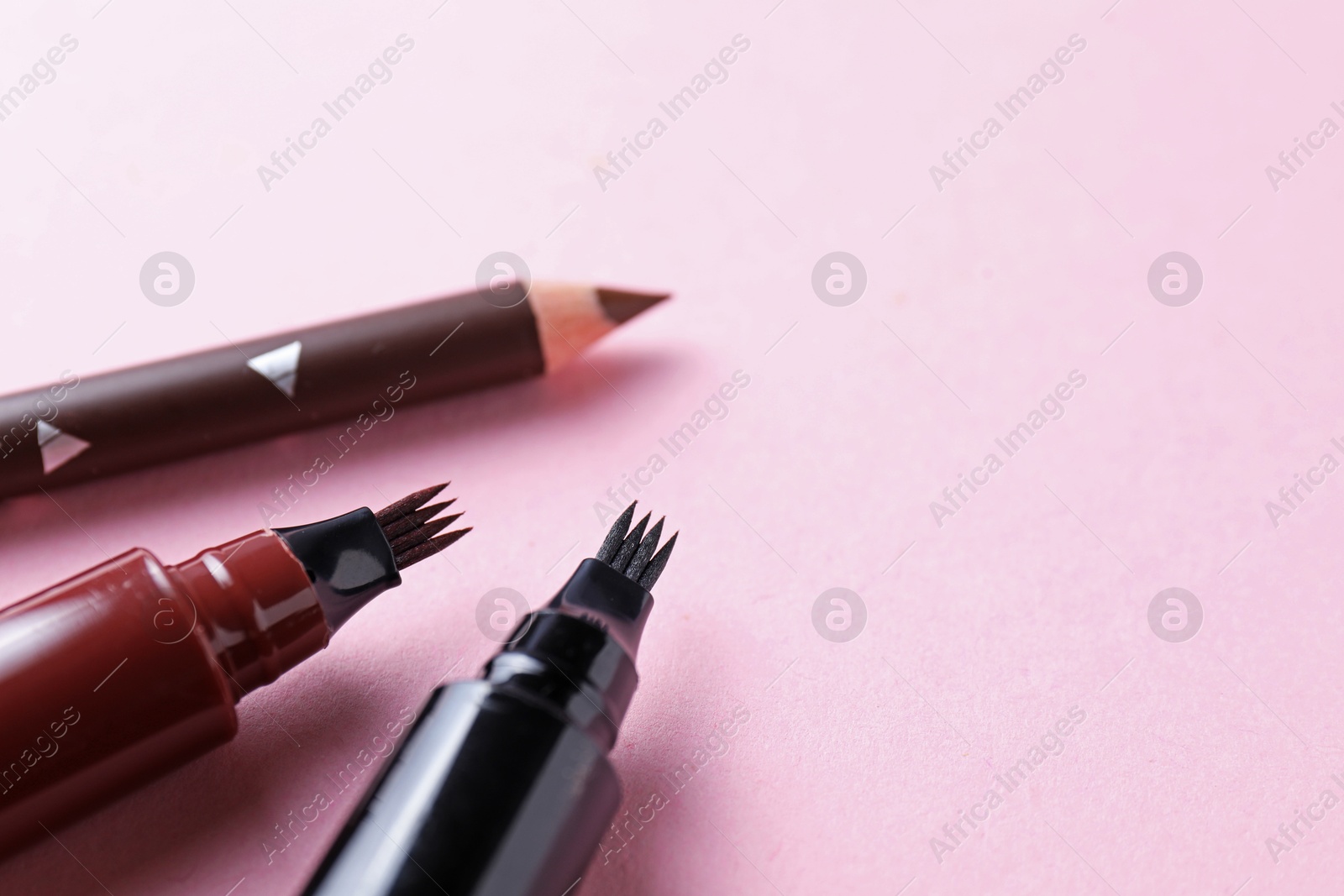 Different eyebrow pencils on pink background, closeup. Space for text Photo of Different eyebrow pencils on pink background, closeup. Space for text