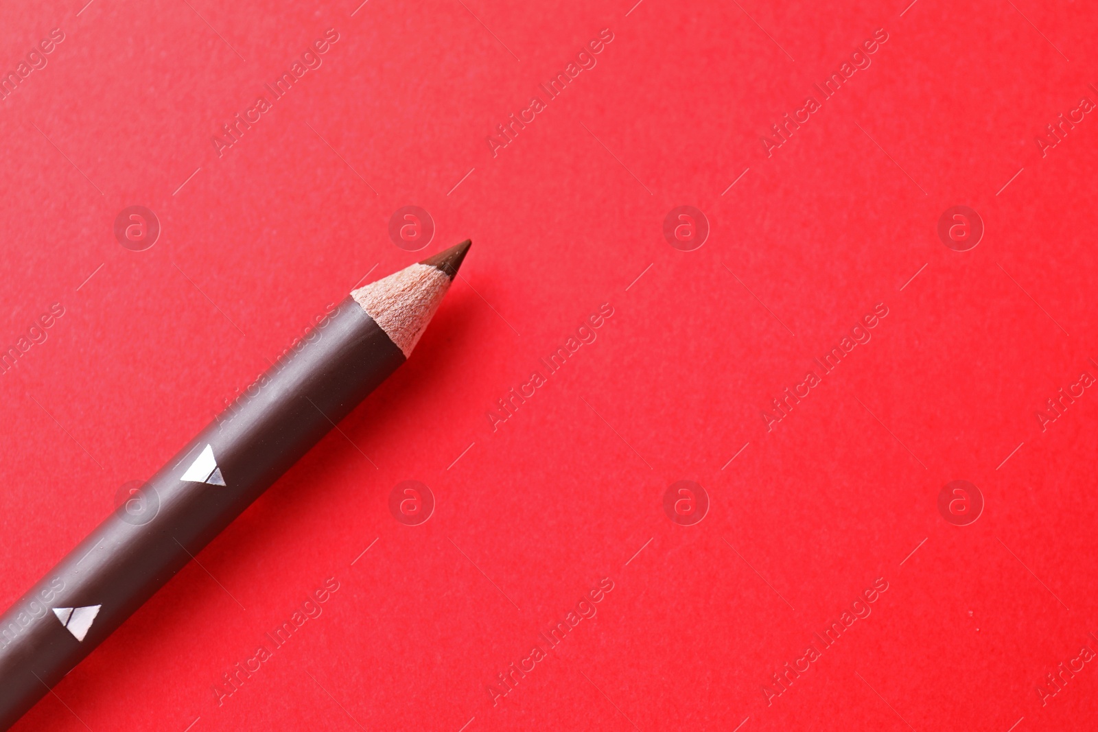 One eyebrow pencil on red background, top view. Space for text Photo of One eyebrow pencil on red background, top view. Space for text