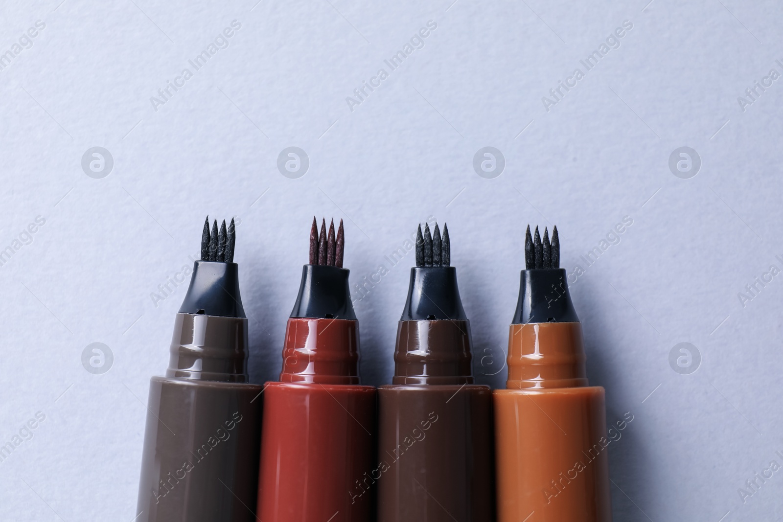 Liquid eyebrow pencils on white background, flat lay Photo of Liquid eyebrow pencils on white background, flat lay