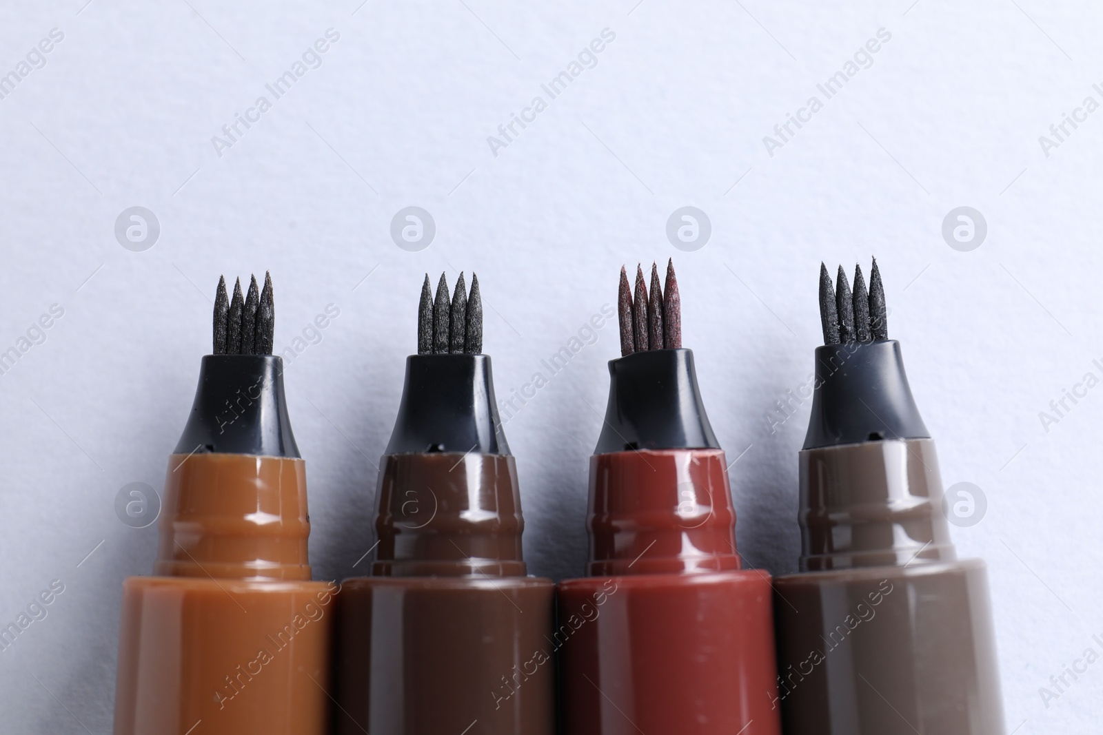 Liquid eyebrow pencils on white background, flat lay Photo of Liquid eyebrow pencils on white background, flat lay