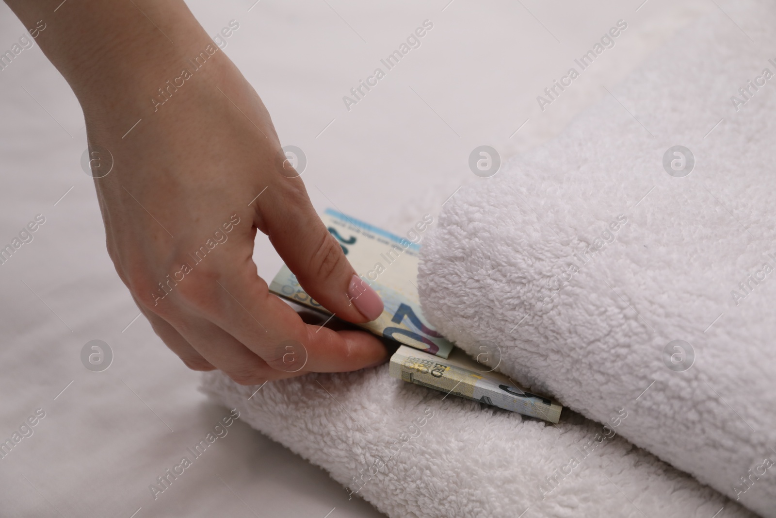 Woman putting tips between towels in hotel, closeup Photo of Woman putting tips between towels in hotel, closeup