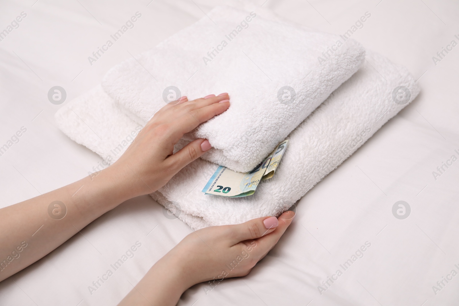 Photo of Woman with tips between towels in hotel, closeup