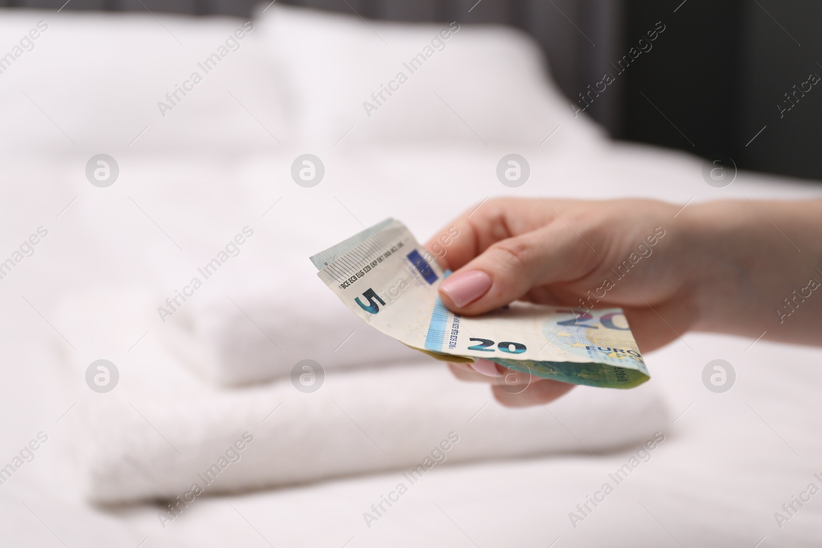 Photo of Woman with tips against bed in hotel, closeup