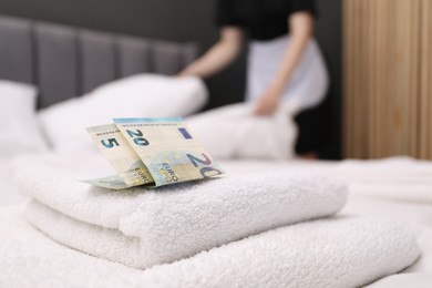 Photo of Chambermaid working in hotel room, focus on tips and towels on bed